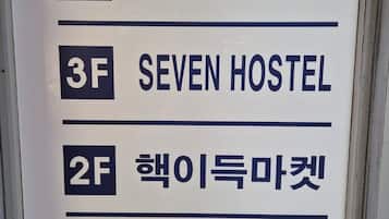 A sign with room numbers and names: 4F Seven Hostel, 3F Seven Hostel, 2F Cheongi Market, B1 Bangbae Tower.