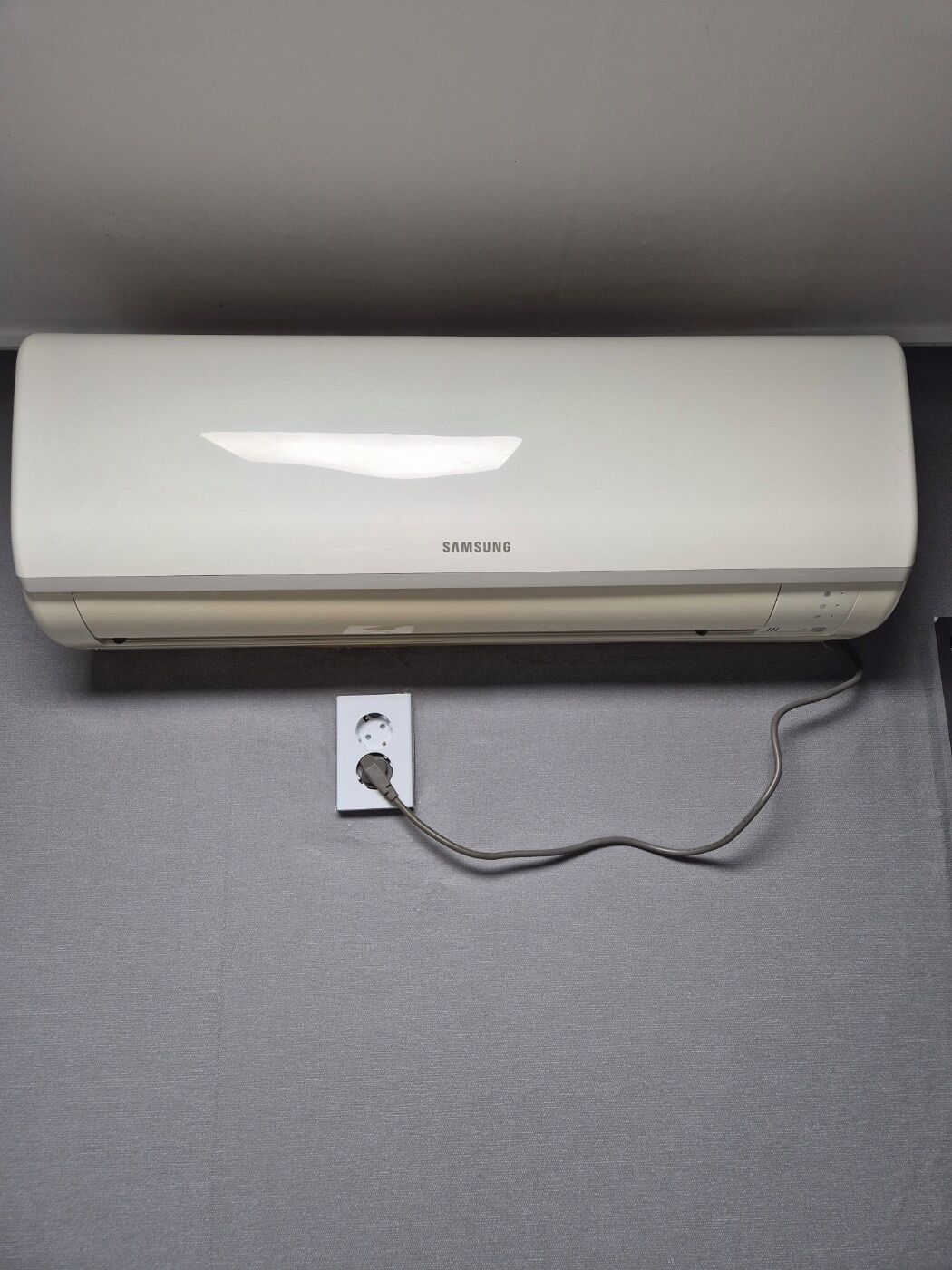 Un climatiseur Samsung posé sur une surface grise.