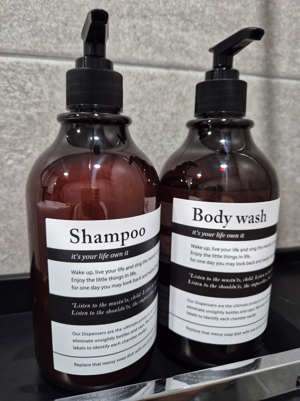 Two bottles of shampoo and body wash with pump dispensers on a countertop.