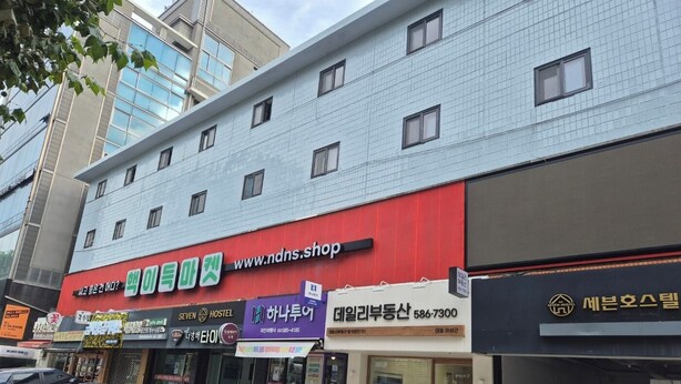A building with multiple storefronts, including a hostel and a shop with a red awning.