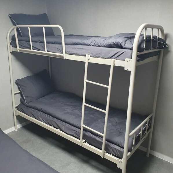 Una cama litera con dos niveles, cada uno con un colchón y almohadas.
