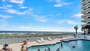 A pool area with lounge chairs and a view of the beach. - Silver Beach 206 by Liquid Life (Orange Beach)