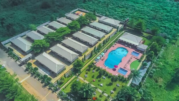 A resort with multiple bungalow-style buildings, a central swimming pool, and lush greenery surrounding the property. - Crown City Resorts  (Agbara)