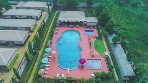 An aerial view of a residential area with a swimming pool surrounded by lounge chairs and umbrellas. - Crown City Resorts  (Agbara)
