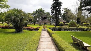 A pathway leading to a gazebo in a well-maintained garden with trimmed hedges and a bench. - Crown City Resorts  (Agbara)
