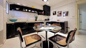 A modern kitchen with a round dining table, black and brown chairs, and a black cabinet above the counter. - Colosseo Way (Roma)