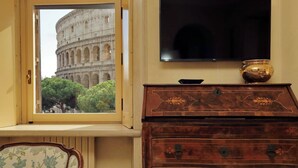 A room with a window view of the Colosseum, a wooden dresser, and a flat-screen TV. - Colosseo Way (Roma)