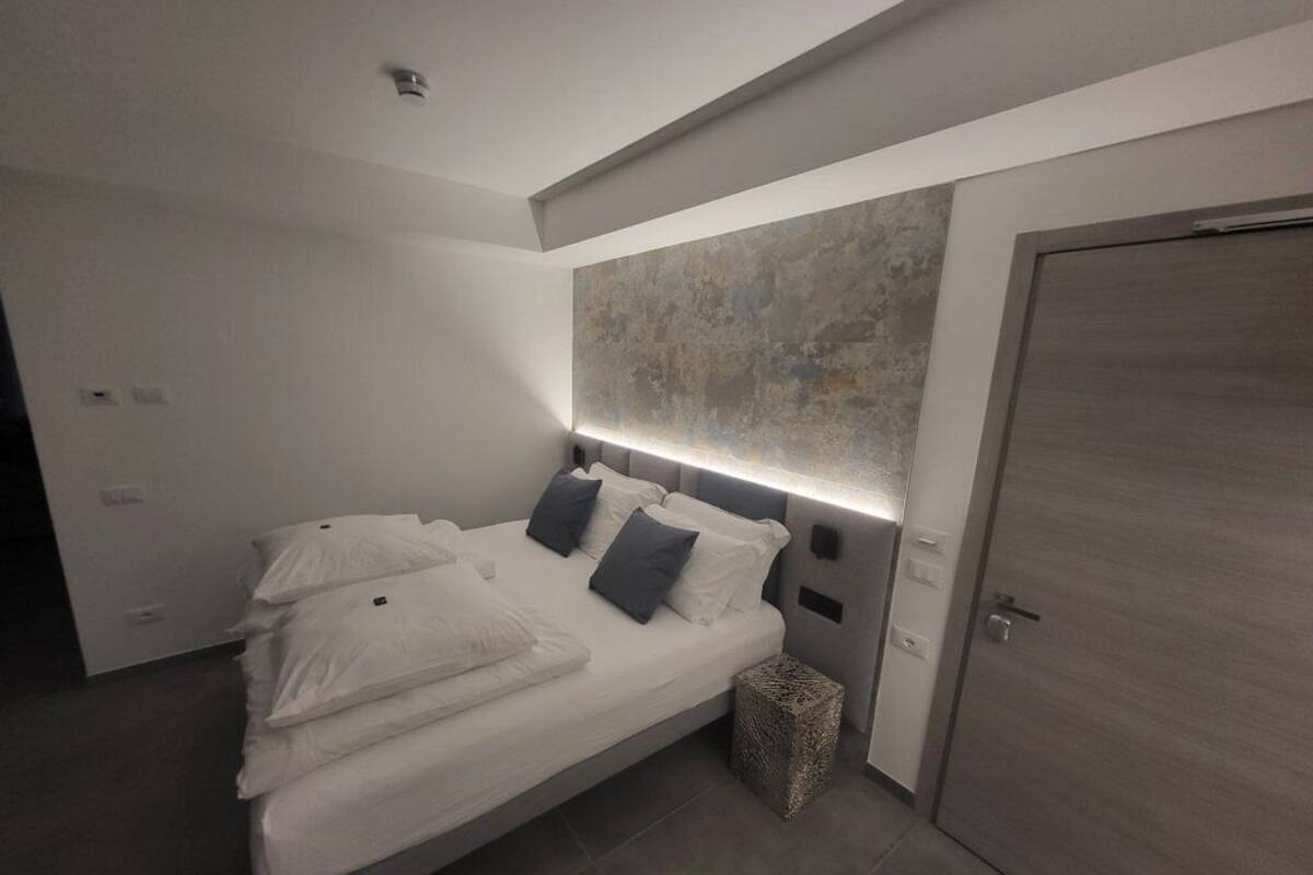 Een moderne slaapkamer met een bed, nachtkastjes en een groot abstract schilderij aan de muur.