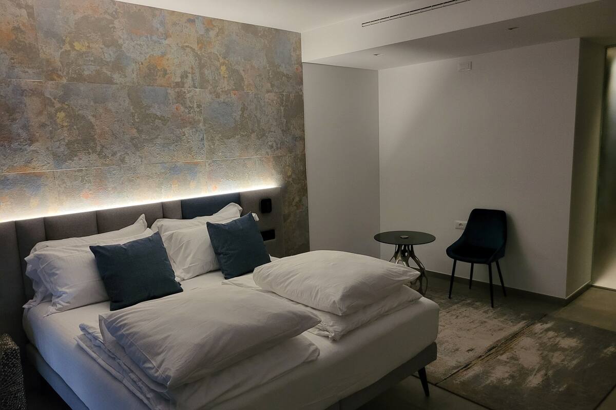 Een moderne hotelkamer met een groot bed, een klein rond tafeltje en twee stoelen.