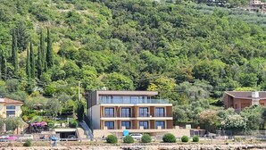A modern two-story building with a flat roof, situated by a body of water. - Attilio High Living Suites - Adults Only (Torri del Benaco)