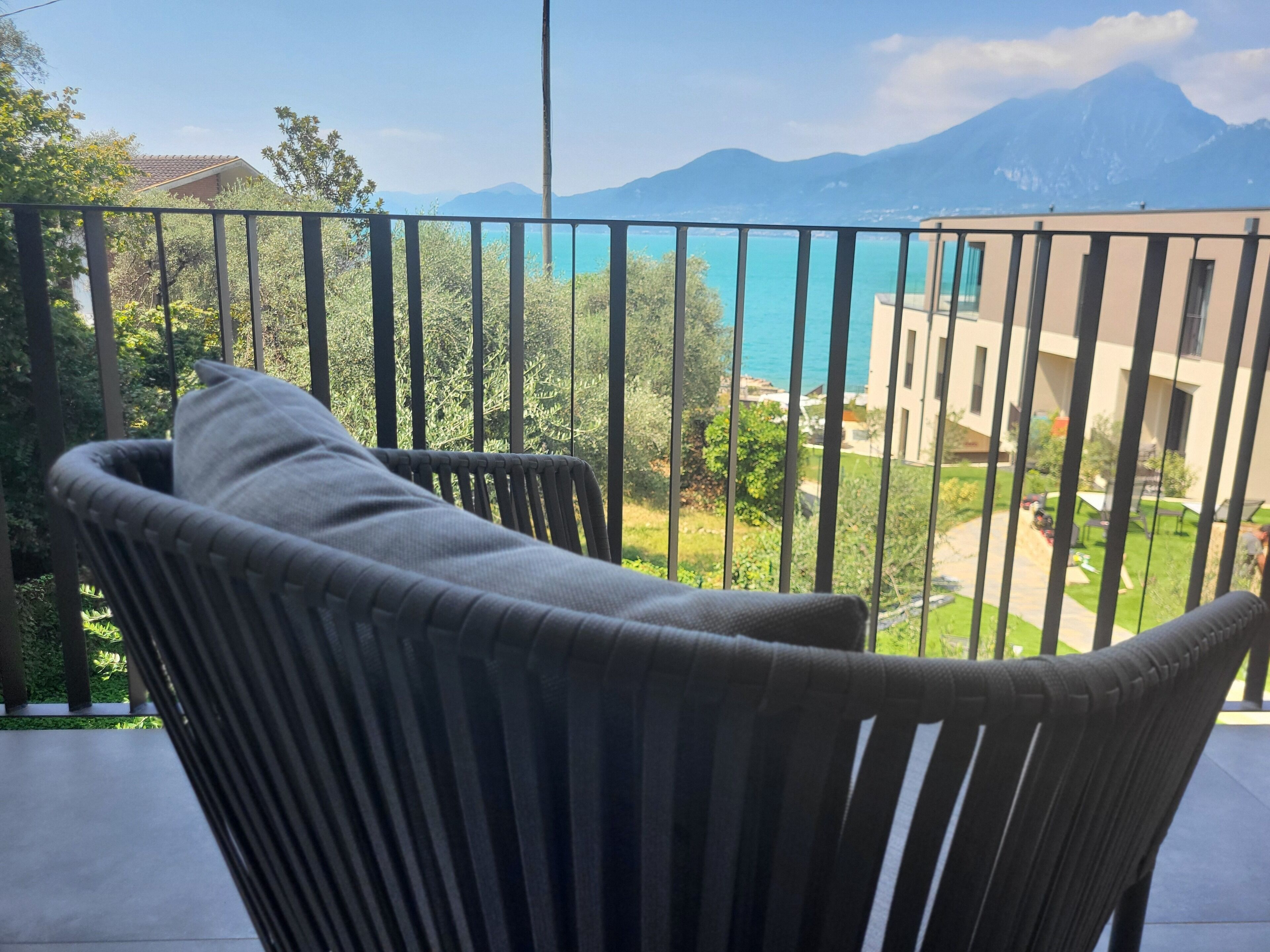 A balcony with a chair and a view of a mountain and a body of water.