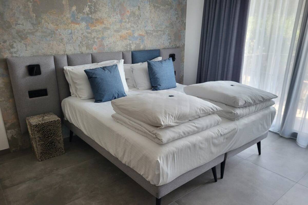 Een moderne slaapkamer met een groot bed, een grijs hoofdeinde en een structuurwand.