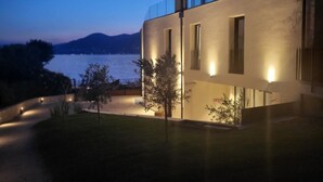A modern building with a flat roof, large windows, and a well-lit exterior. - Attilio High Living Suites - Adults Only (Torri del Benaco)