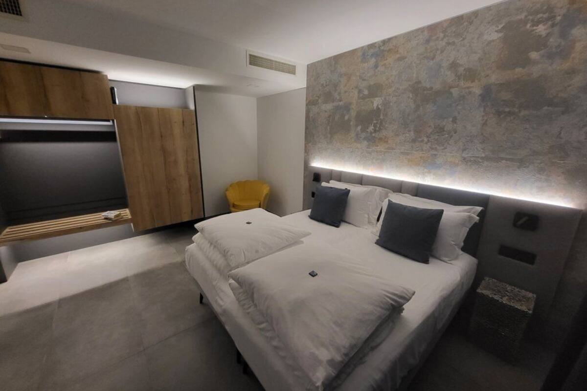 Een moderne slaapkamer met een groot bed, een televisie en een unieke, structuurrijke wand.