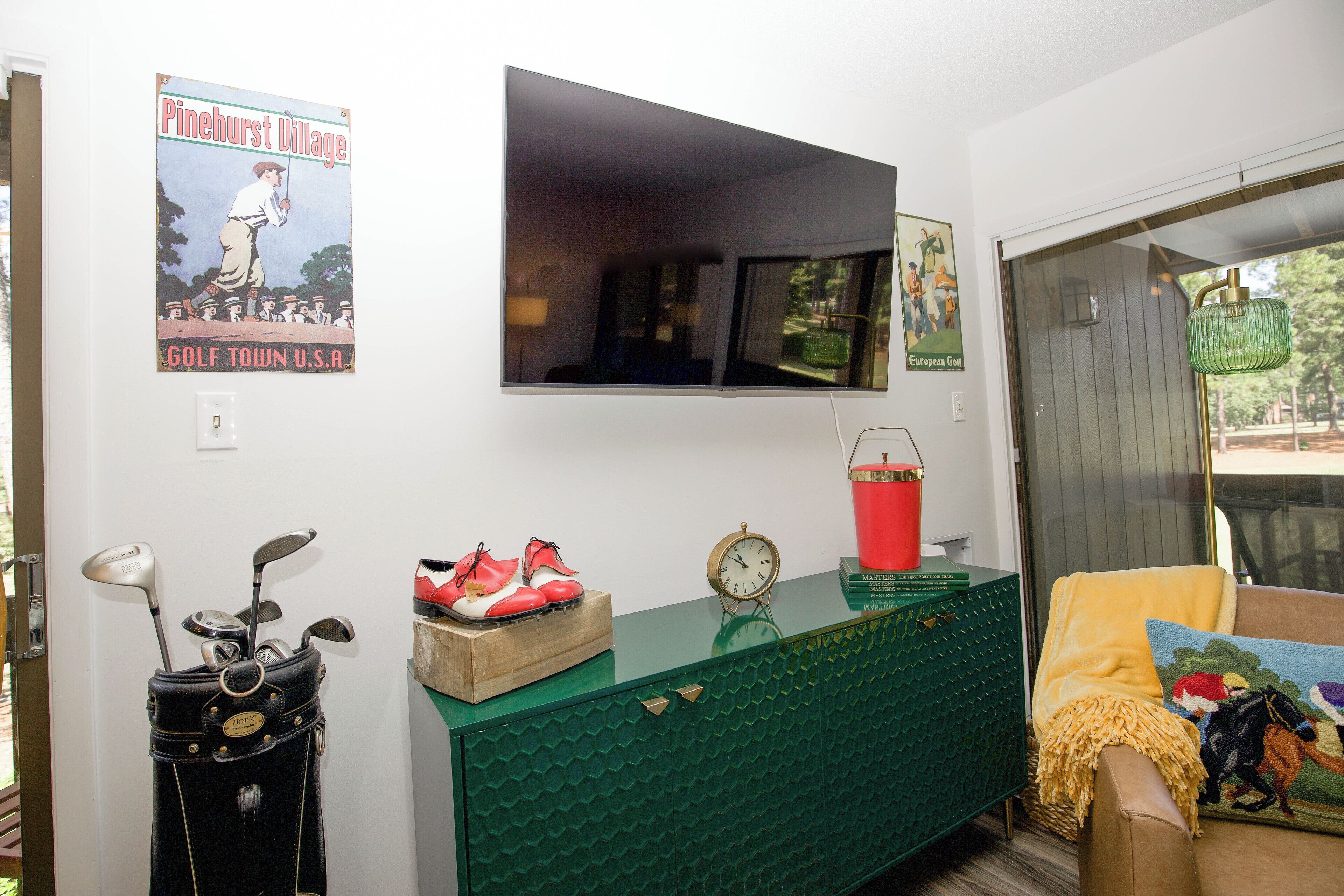 A room with a green cabinet, a clock, and a poster on the wall.