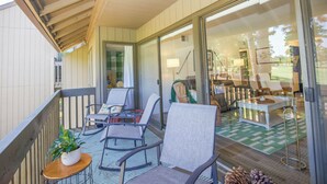 Ein Balkon mit Sitzgelegenheit im Freien, einem Blumentopf und Blick ins Innere durch Glastüren.