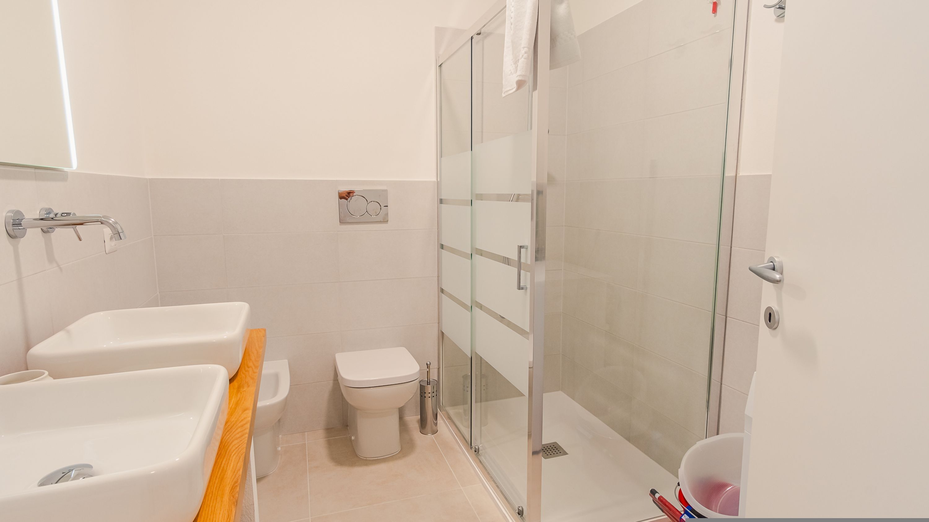 A modern bathroom with a bathtub, toilet, and glass shower enclosure.