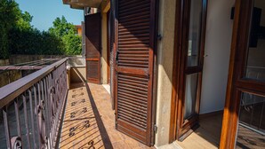 Ein Balkon mit Metallgeländer, Holzläden und Fliesenboden.