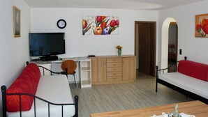 Un salon avec un téléviseur, un canapé et un coin repas.