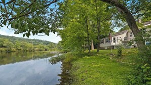 Blick auf einen Fluss mit einem Haus und üppigem Grün.