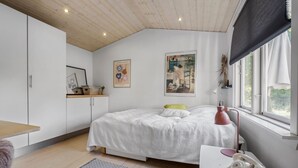 A bedroom with a bed, a desk, a chair, a lamp, and a window.