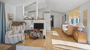 A cozy living room with a sofa, a TV, a bookshelf, and a wooden cabinet.