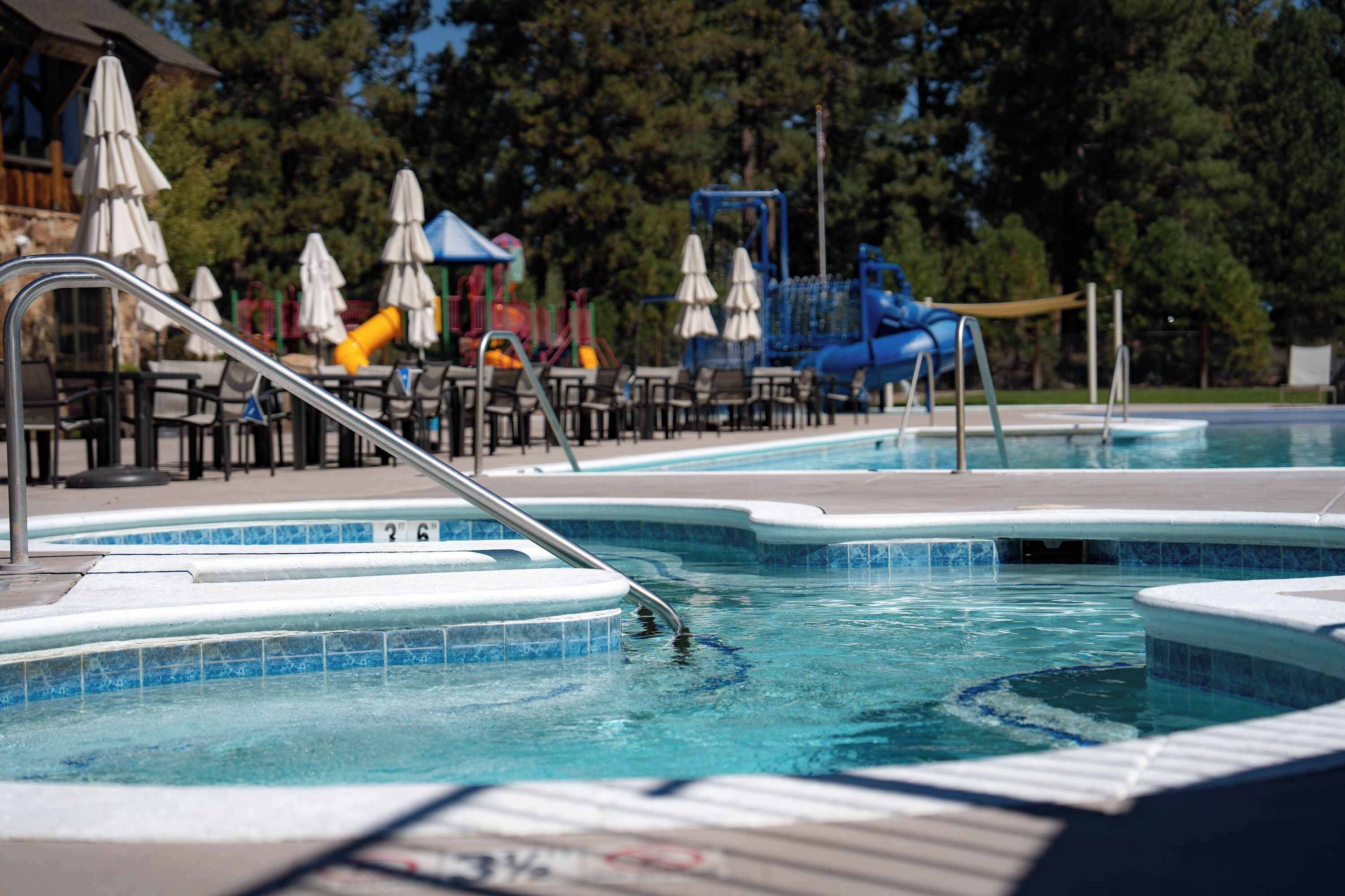 Piscina com várias pistas de natação, área de recreação infantil e área de estar ao ar livre.