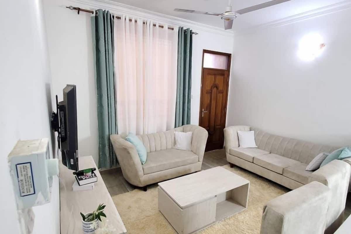 Ein Wohnzimmer mit zwei Sofas, einem Couchtisch, einem Fernseher und einem Deckenventilator.