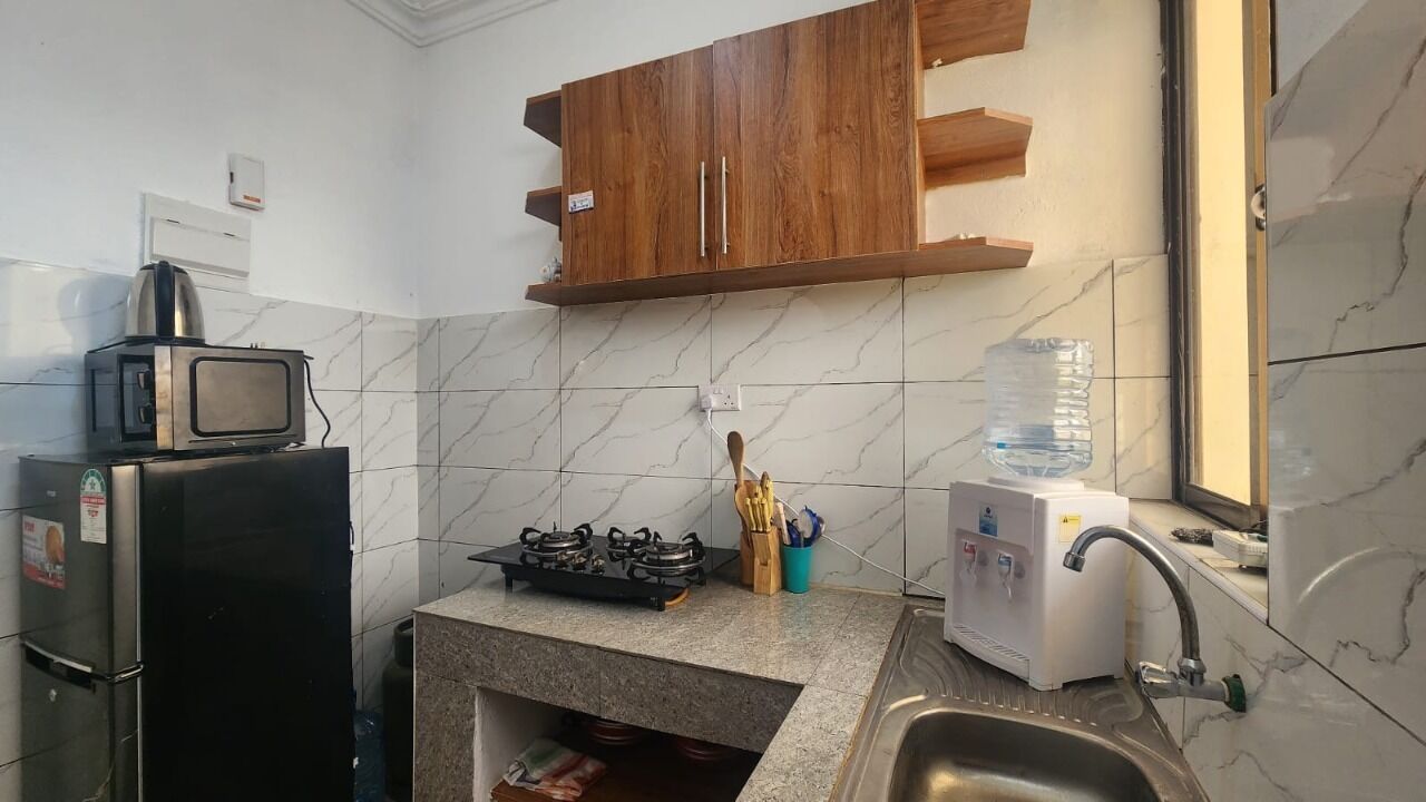 A compact kitchen with a microwave, gas stove, sink, and wooden cabinets.