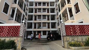 A multi-story hotel with a central courtyard, balconies on each floor, and a clear sky above. - Casey's Apartments Bamburi (Mombasa)