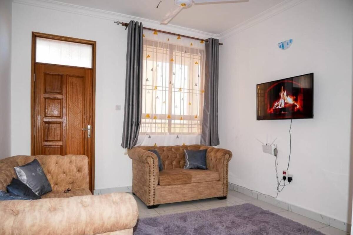 Ein Wohnzimmer mit zwei Sofas, einem Fernseher und einem Fenster mit Vorhängen.