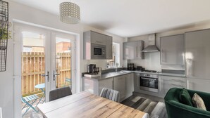 Una cocina moderna con armarios grises, una mesa de comedor de madera y un sofá verde.