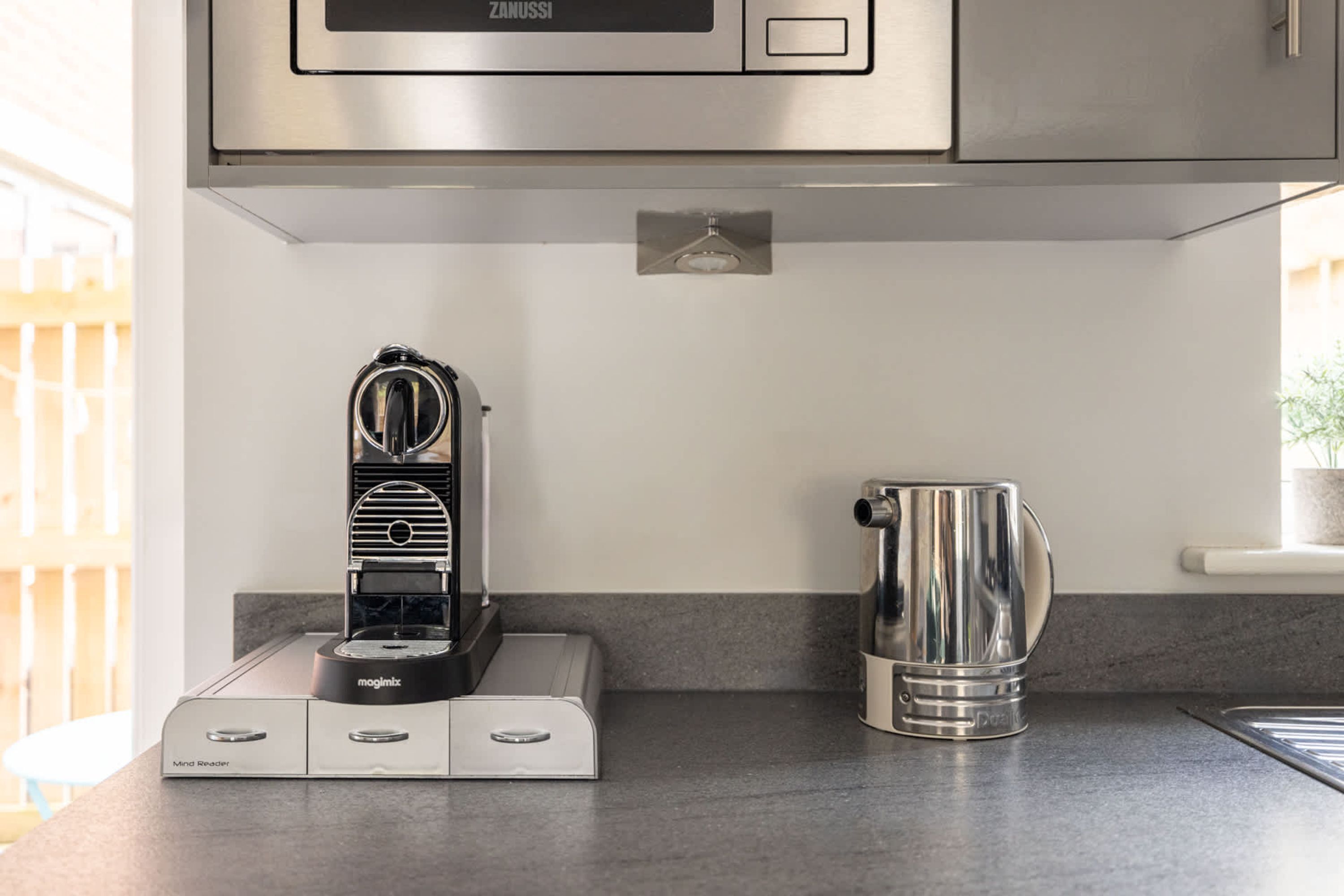 A kitchen with a coffee machine, a kettle, and a microwave.