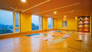 Ein geräumiges Zimmer mit großen Fenstern, Holzböden und mehreren ausgelegten Yogamatten.