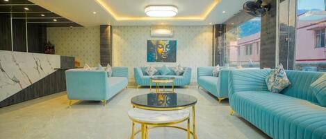 A modern living room with teal sofas, a central coffee table, and a marble accent wall.