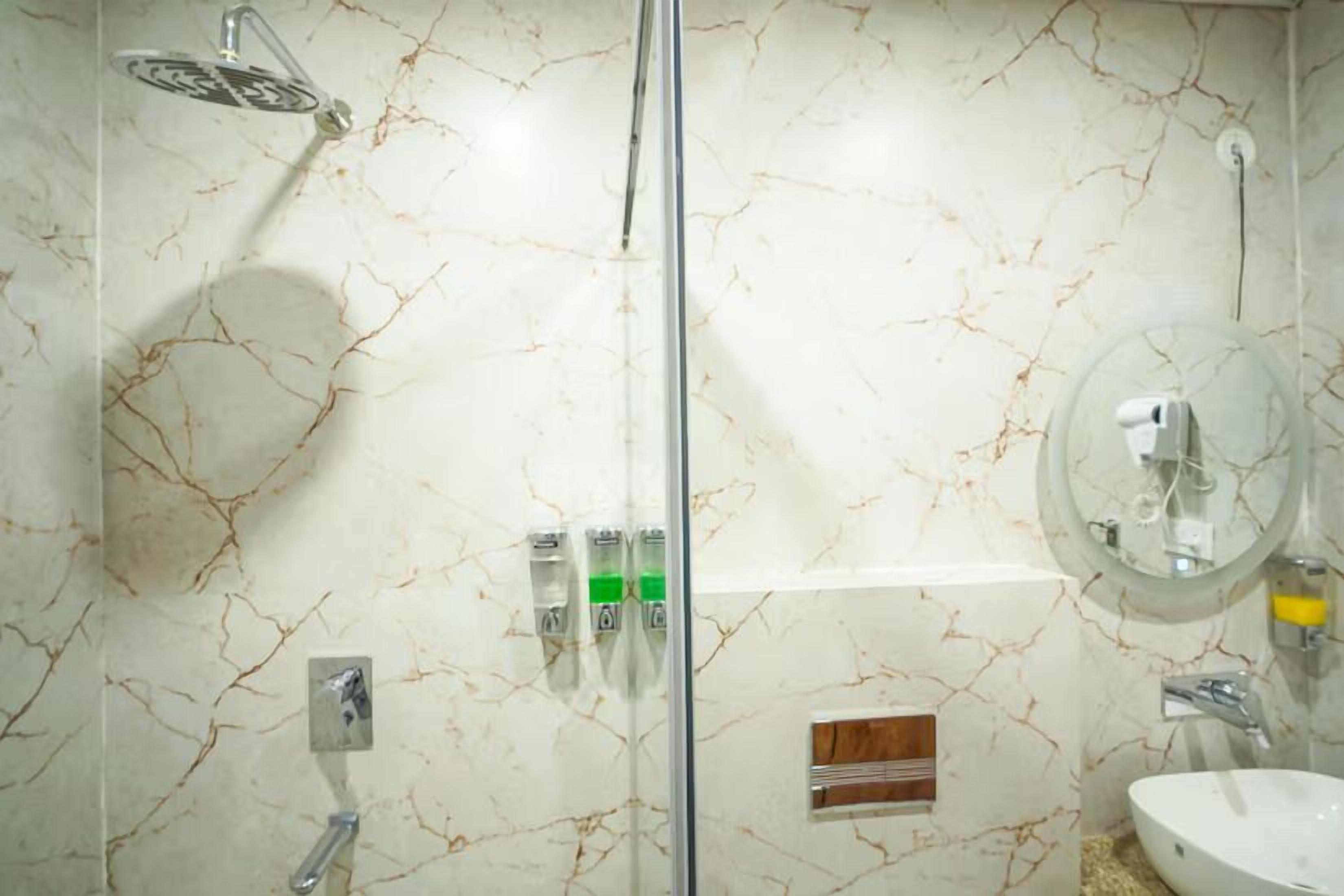 Ein Badezimmer mit einer Duschkabine, einem Waschbecken und einem Spiegel.