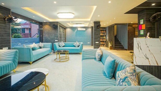 Ein modernes Wohnzimmer mit türkisfarbenen Sofas, einem Marmortisch und einem Bücherregal.