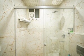 Ein Badezimmer mit Duschkabine aus Glas, Marmorwänden, einem Handtuchhalter und einer Seifenspender.