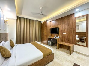 Ein Hotelzimmer mit Bett, Schreibtisch und Fernseher.