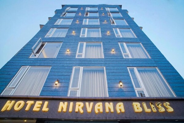 Ein Hotelgebäude mit modernem Design, mit zahlreichen Fenstern und einer Beschriftung, die „HOTEL NIRVANA BLISS“ zeigt.