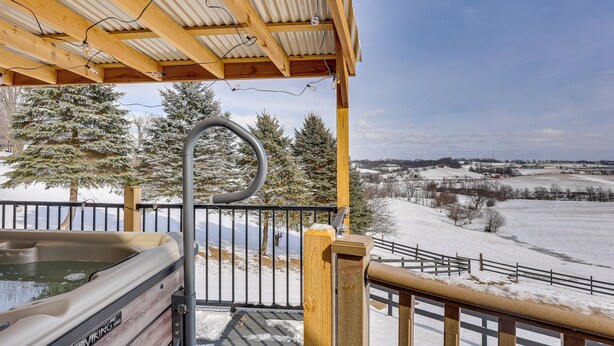 A wooden deck with a hot tub, metal railing, and a view of snow-covered landscape. - 'Holmes With a View' Studio: Millersburg Retreat! (Millersburg)