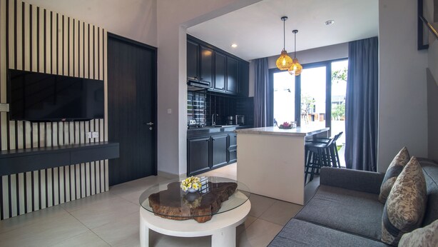 A modern living room with a glass coffee table, a sofa, and a TV mounted on the wall. - Casa de la Vida (Tabanan)
