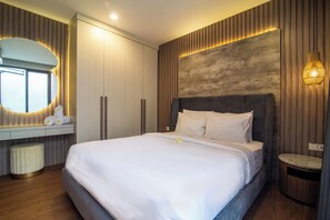 A modern bedroom with a large bed, a built-in wardrobe, a bedside table, and a round mirror. - Casa de la Vida (Tabanan)