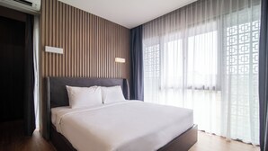 A modern hotel room with a large bed, wooden panel wall, and a view through sheer curtains. - Casa de la Vida (Tabanan)