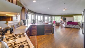 Una cocina amplia con isla central, piso de madera y ventanas grandes.