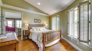 Un dormitorio con cama de madera, mesitas de noche, un buró y una cómoda.