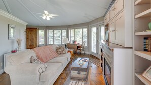 A spacious living room with a large sofa, a coffee table, and a fireplace. There are multiple windows providing natural light and a view of the outdoors. - Panoramic Views: Hillside Millersburg Studio (Millersburg)