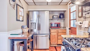 A compact kitchen with a stainless steel refrigerator, a microwave, and a gas stove.
