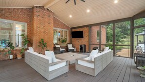 Een overdekt terras met bakstenen muren, witte meubels en een plafondventilator.