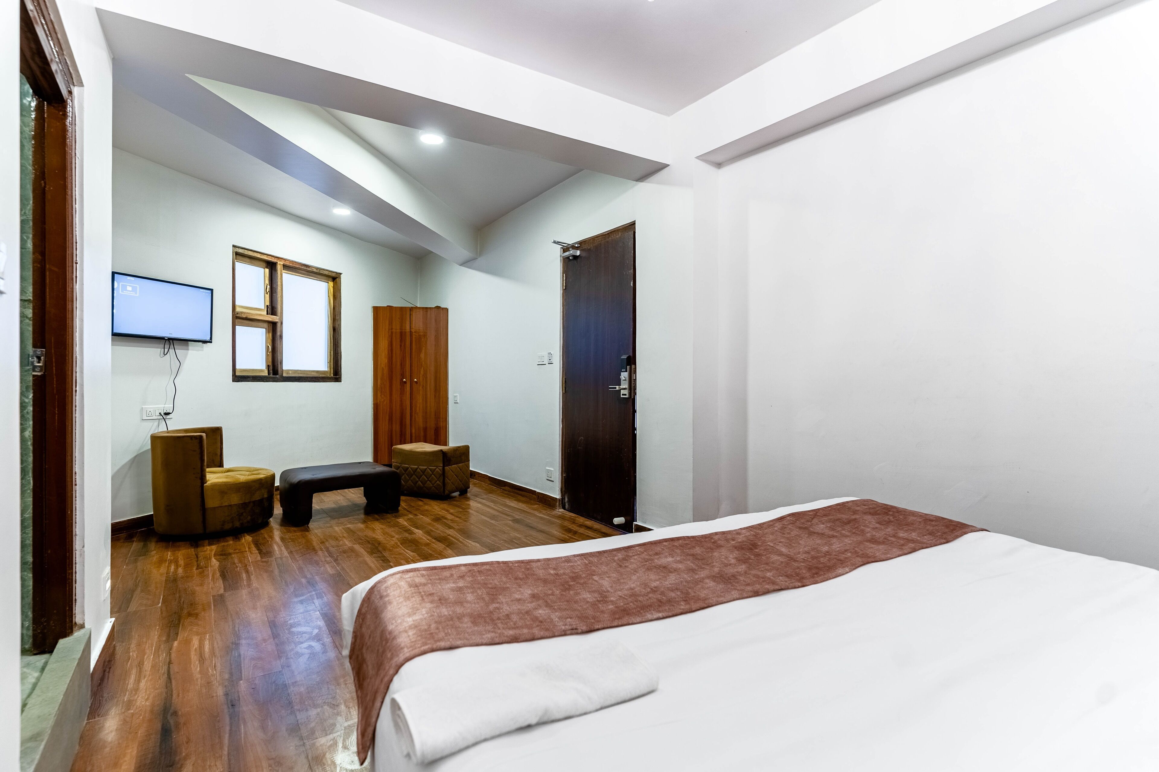 A bedroom with a bed, a bench, a television, and a wardrobe.